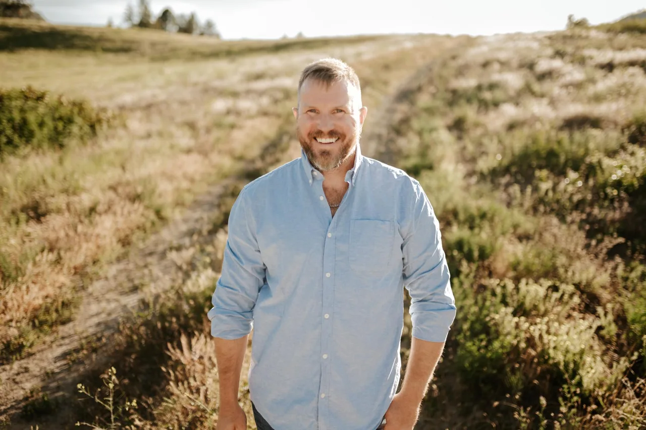 Cameron Pasemko, owner of Semko Contracting, standing in a grassy field at sunset