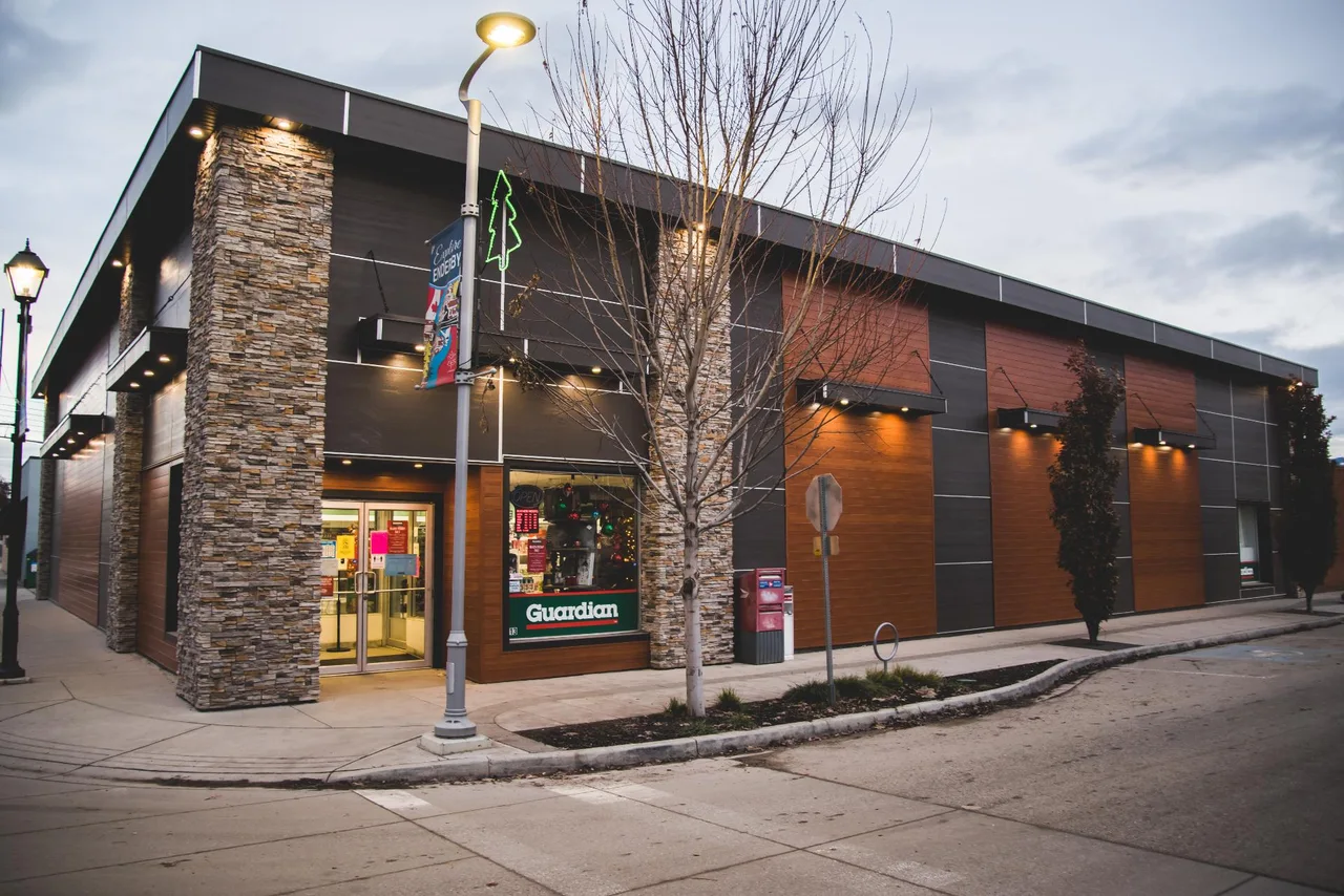 A renovated commercial building on a street corner with stacked stone pillars and wood and dark metal cladding