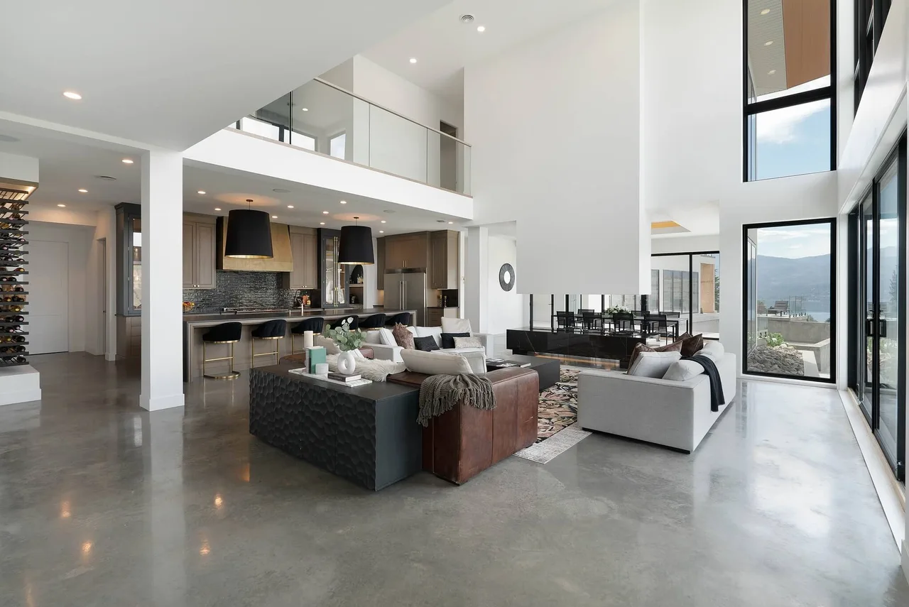 The open main floor: living room, kitchen and dining under a glass-railed upper landing