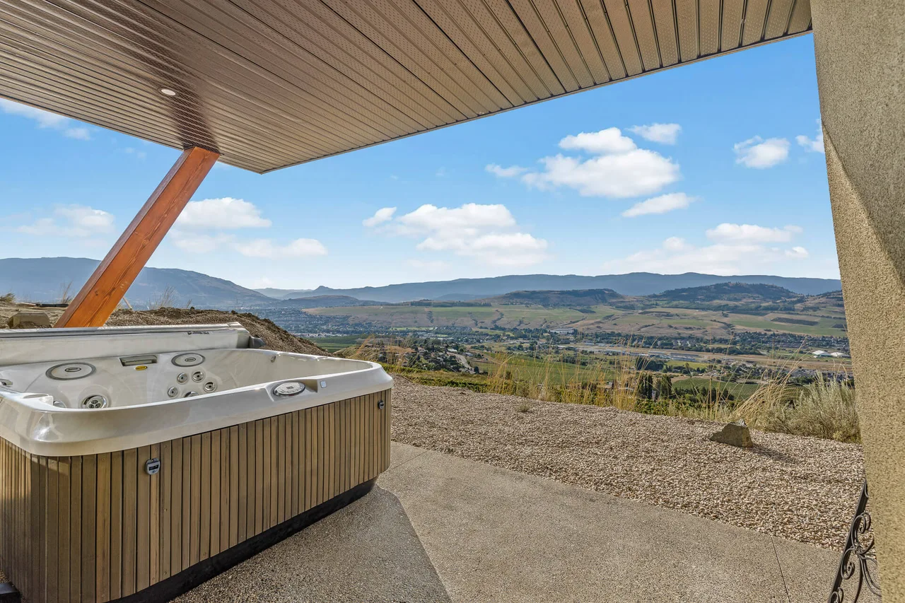 A covered patio with a hot tub, looking out over the valley