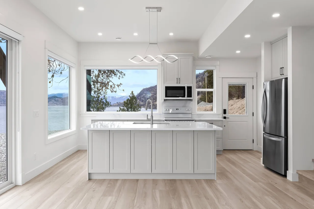 The kitchen island with shaker cabinets and quartz, with a window over the lake